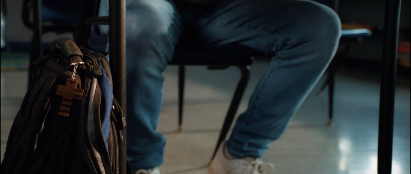 A backpack on the floor beside a school desk.